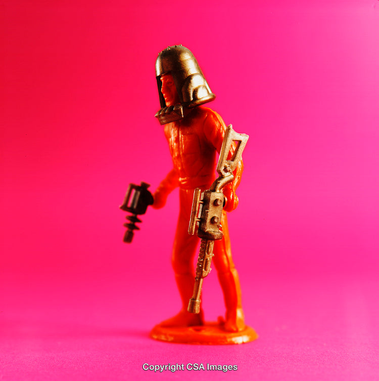 Orange Plastic Toy Figure Against a Vibrant Pink Background