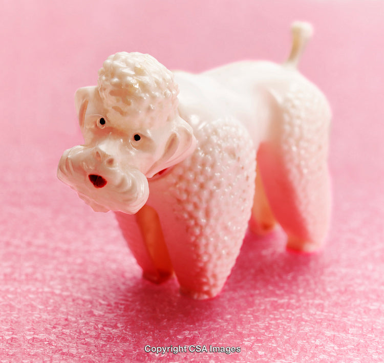 Vintage White Poodle Figurine Against Pink Background and Textured Surface