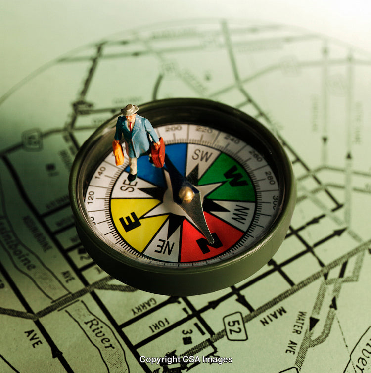 Miniature Traveler Standing on Compass Over City Map