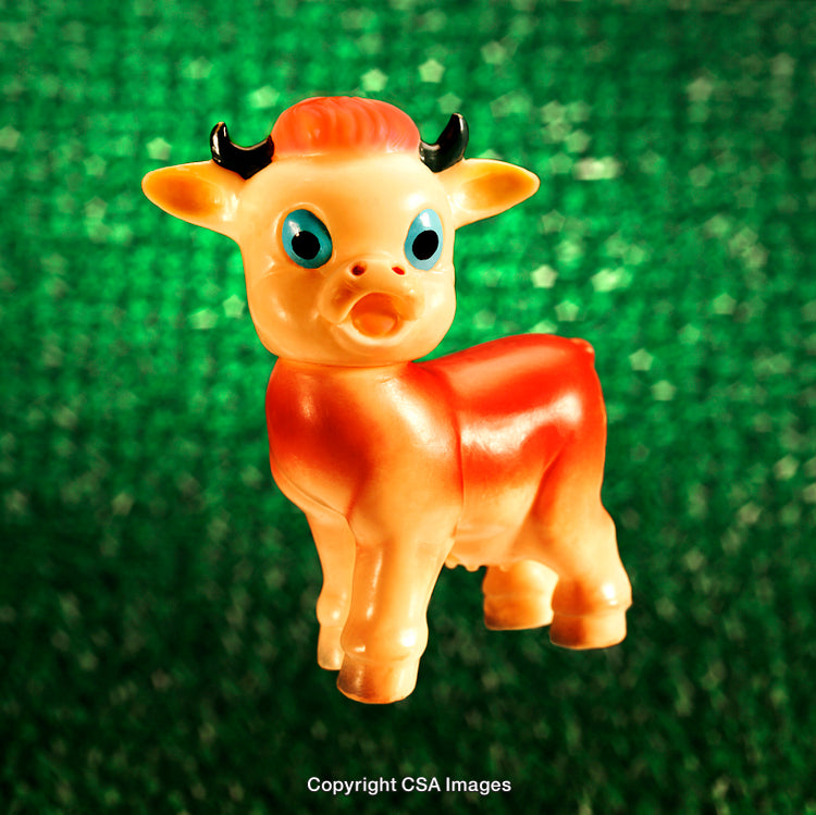 Colorful Plastic Baby Cow Toy Against a Glittering Green Background