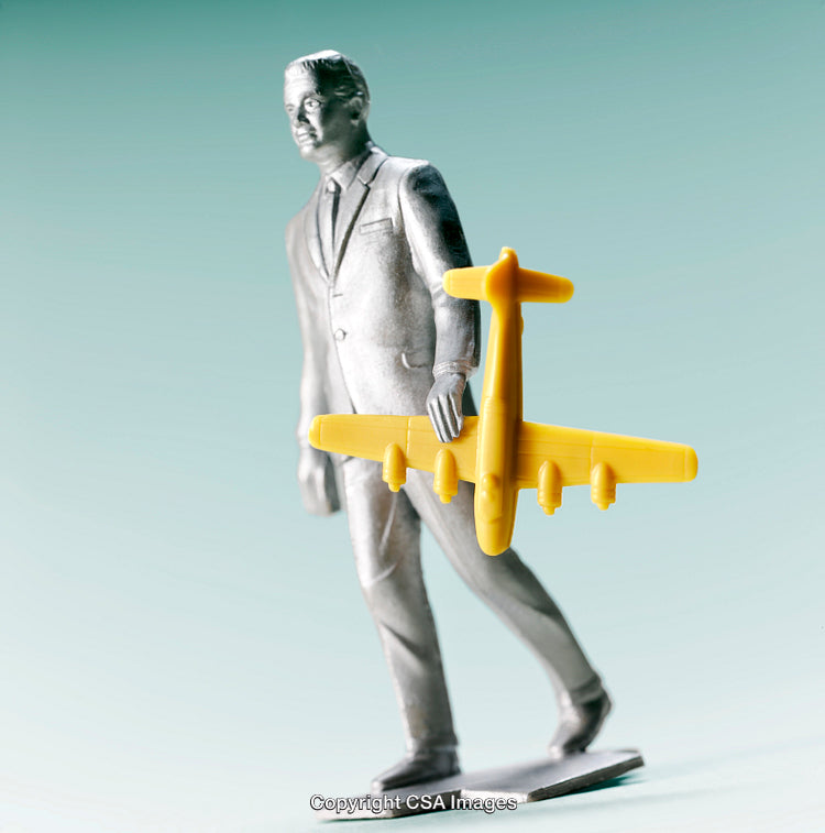 Silver Figurine With Yellow Toy Airplane Against Green Gradient Background