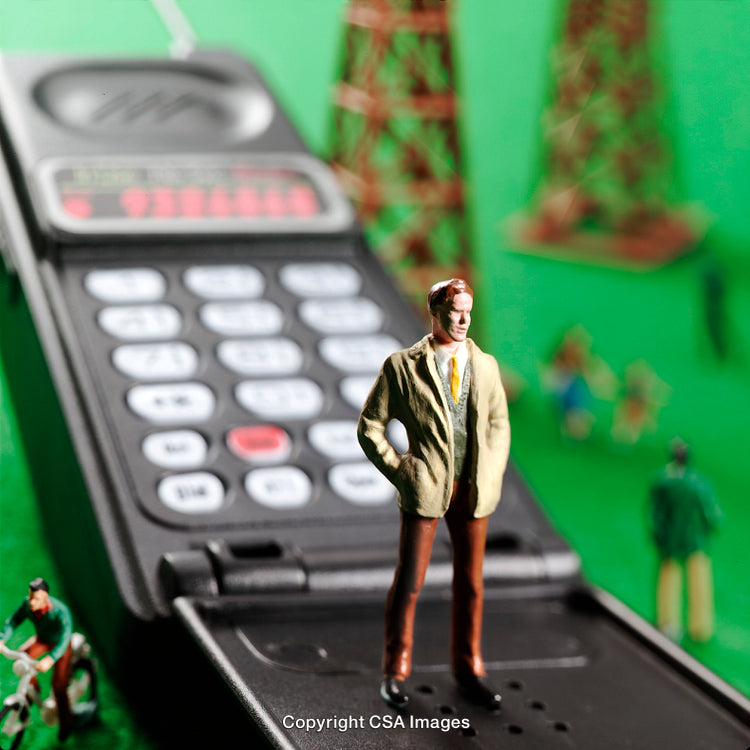 Miniature Figure Stands on Toy Telephone With Green Background