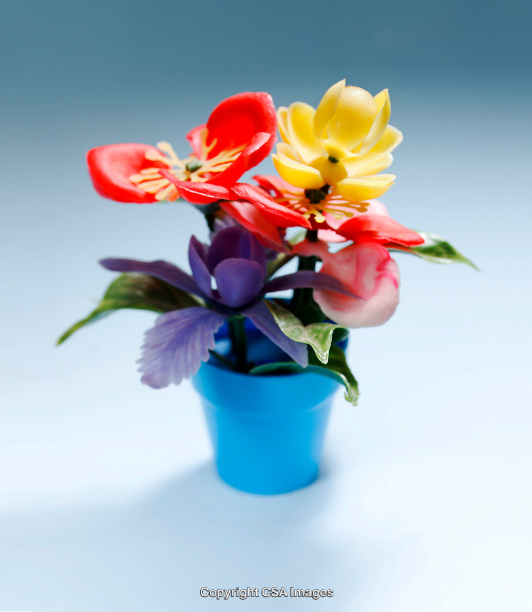 Colorful Plastic Toy Flowers in a Blue Vase on a Light Background