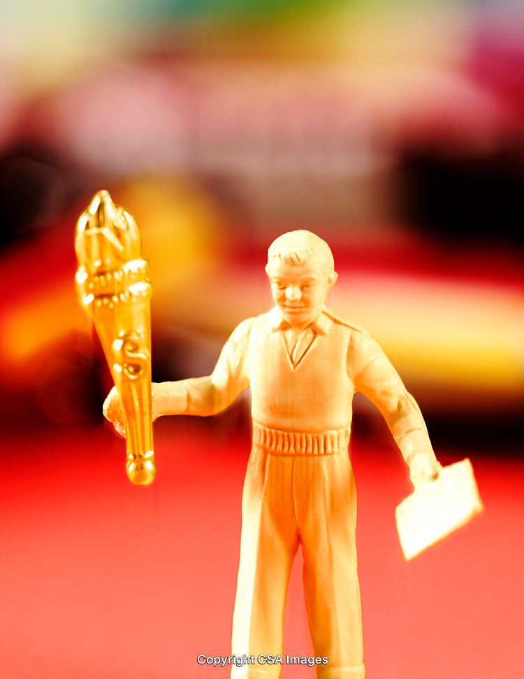 Close-Up of a Plastic Figurine Holding a Torch on a Colorful Background