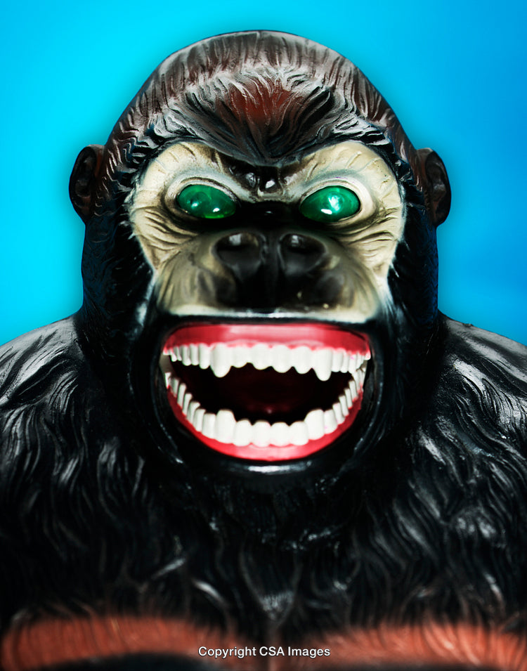 Close-Up of Fierce Gorilla Toy with Green Eyes and Open Mouth on Blue