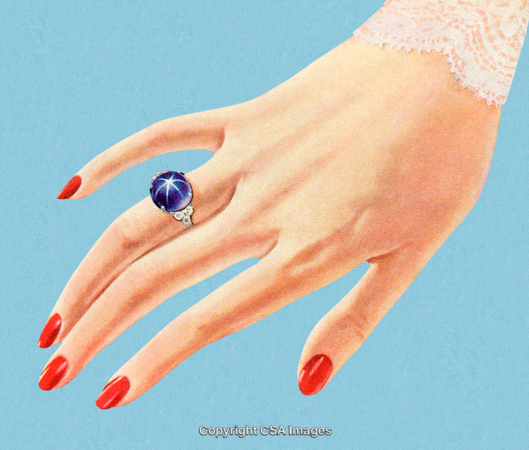 Elegant Female Hand With Blue Gemstone Ring and Red Nail Polish