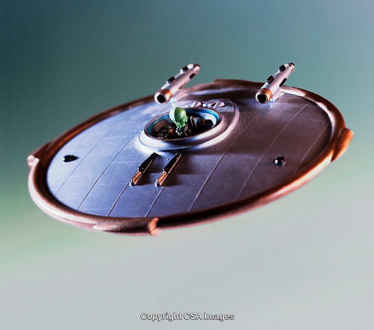 Model UFO Spaceship with Alien Figure on Green Backdrop
