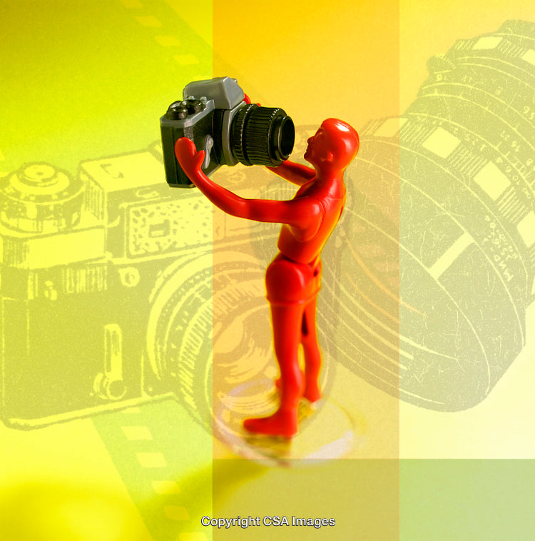 Red Figurine Holding Camera Against Yellow Artistic Background with Lens Diagram