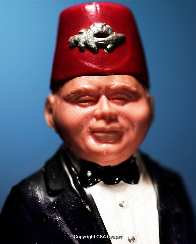 Close-Up of a Plastic Figurine Wearing a Fez Hat and Formal Attire
