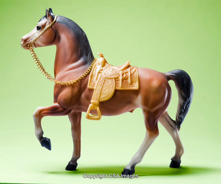Elegant Plastic Toy Horse with Saddle Against a Green Background