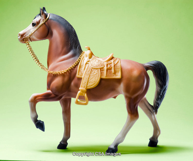 Elegant Plastic Toy Horse with Saddle Against a Green Background