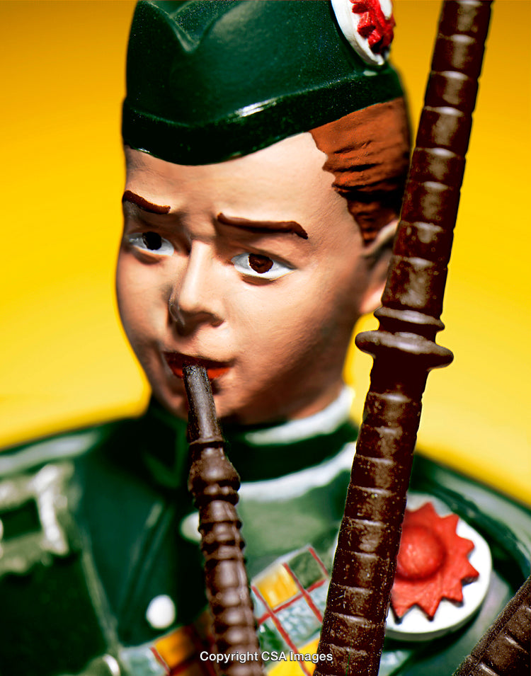 Close-Up of a Scottish Piper Figurine on a Yellow Background