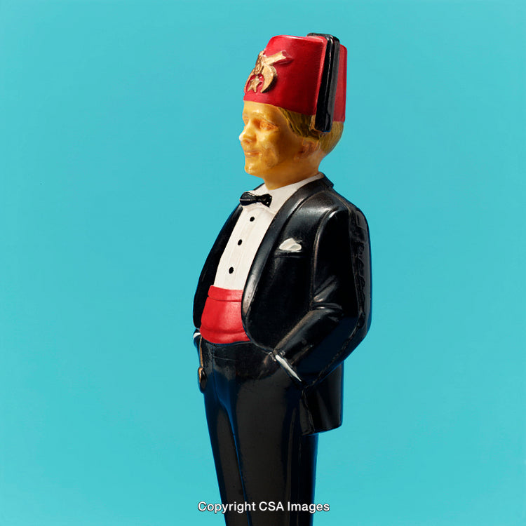 Vintage Toy Figurine in Tuxedo with Red Fez on Blue Background