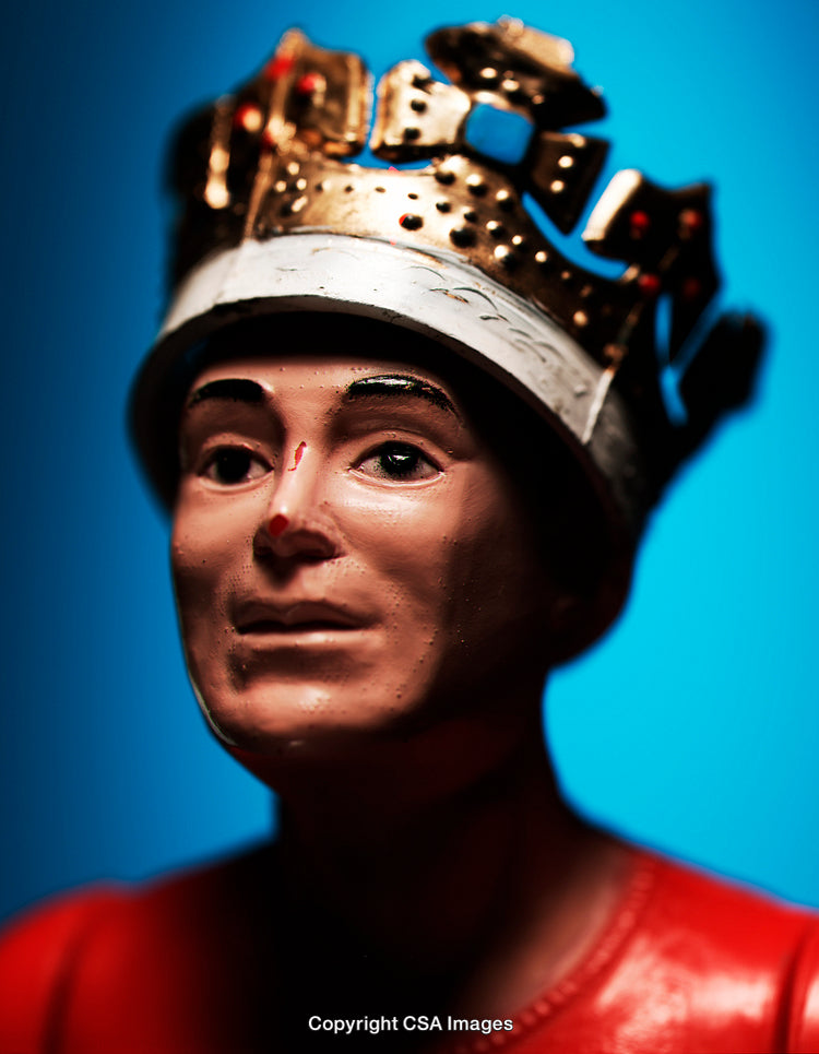 Close-Up of Regal Plastic Figurine With Crown on Blue Background