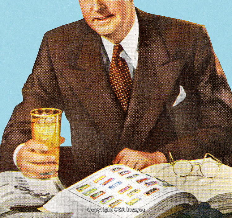 Man in Suit Reviewing Materials While Holding a Glass of Beverage
