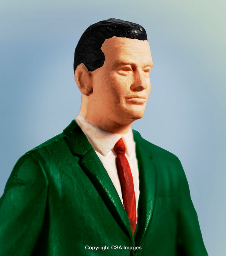 Close-Up of a Toy Figure in Formal Attire on a Blue Background