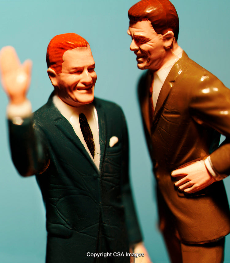 Close-Up of Two Plastic Figurines in Business Suits Interacting