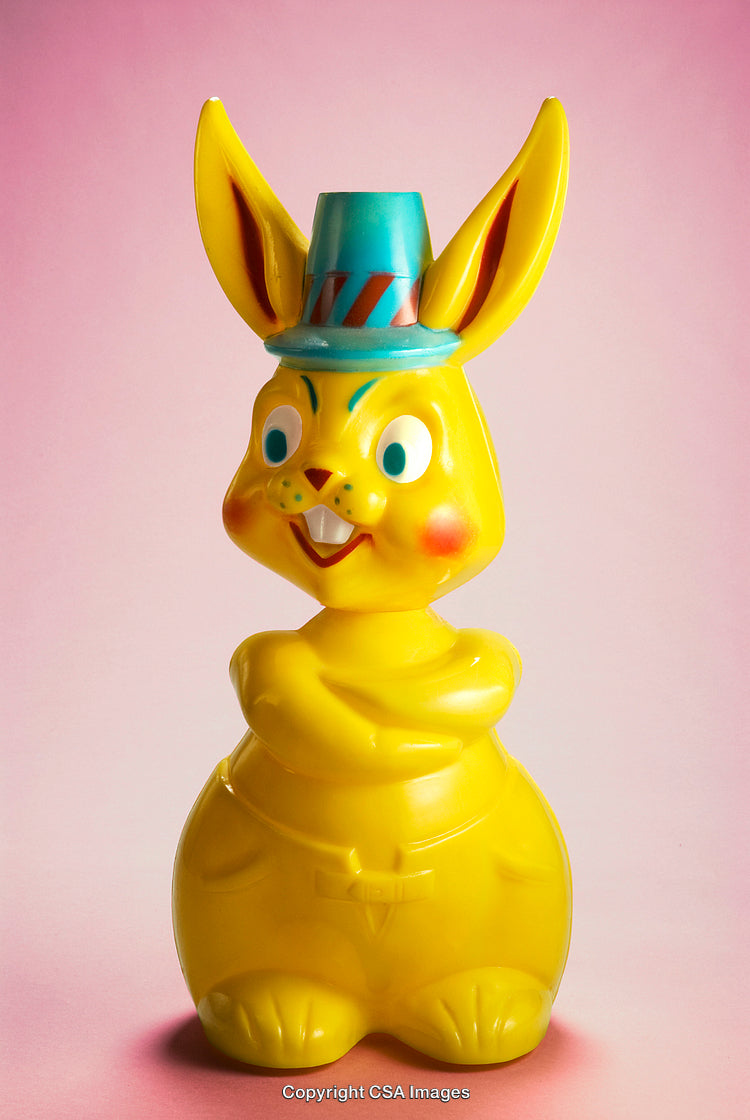 Bright Yellow Plastic Bunny Figure Against Pink Background