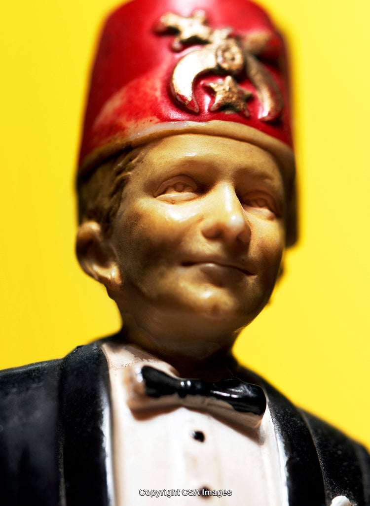 Close-Up of Figurine with Red Hat on Bright Yellow Background