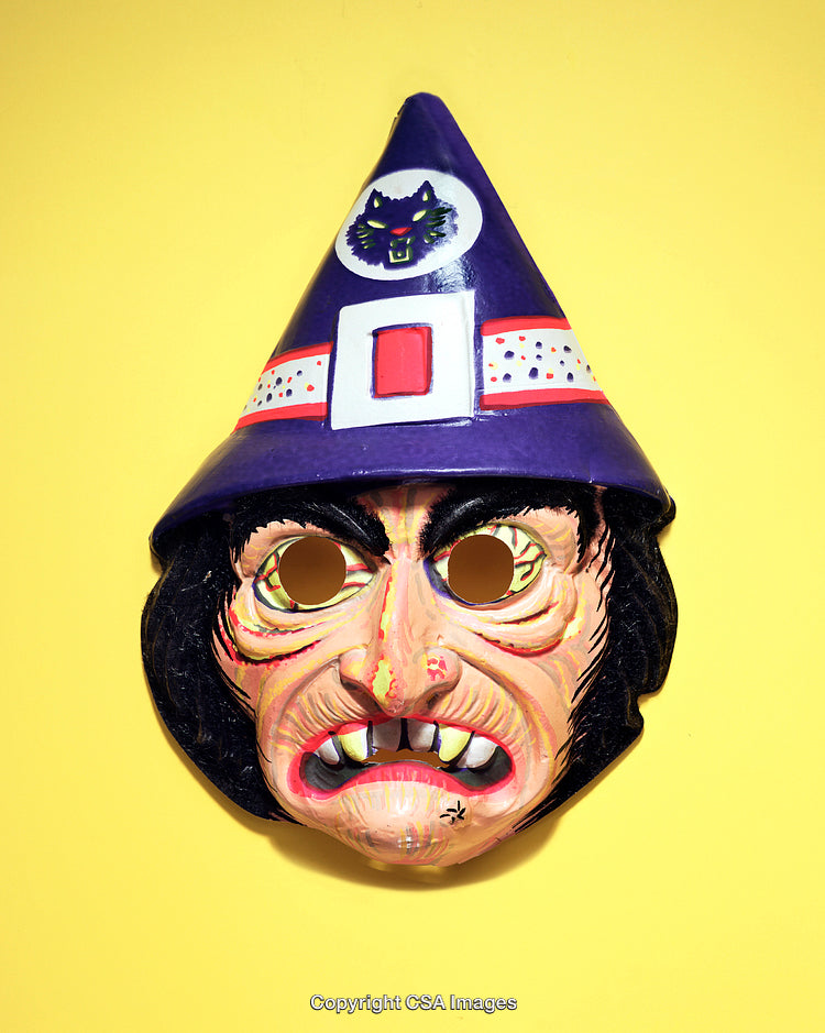 Close-Up of Spooky Witch Mask with Pointed Hat on Bright Yellow Background