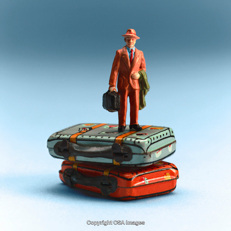 Miniature Traveler Standing on Stacked Colorful Suitcases Against Blue Background