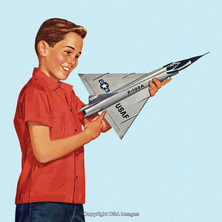 Smiling Boy Holding and Admiring a Model Fighter Jet Aircraft