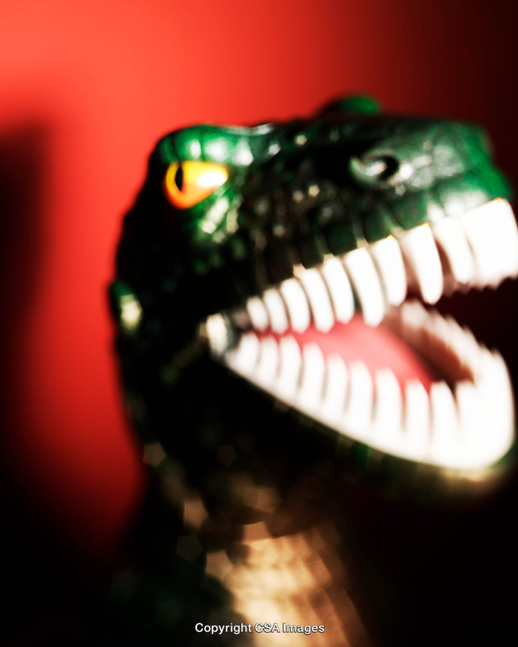 Close-Up of Toy Dinosaur Against Red Background in Dramatic Lighting