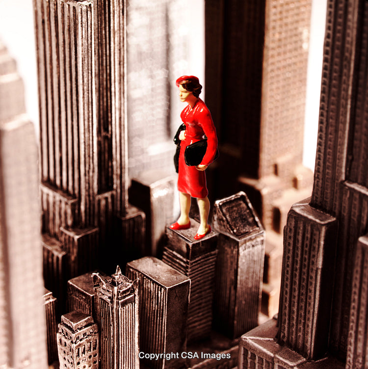 Miniature Woman in Red Standing Among Tall Urban Skyscrapers
