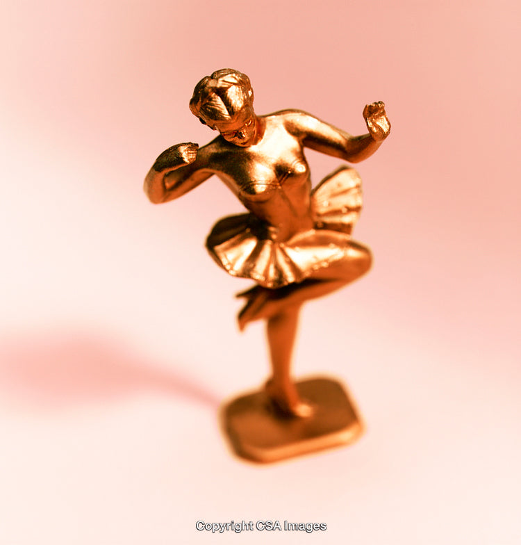 Golden Ballet Figurine Against Soft Pink Background