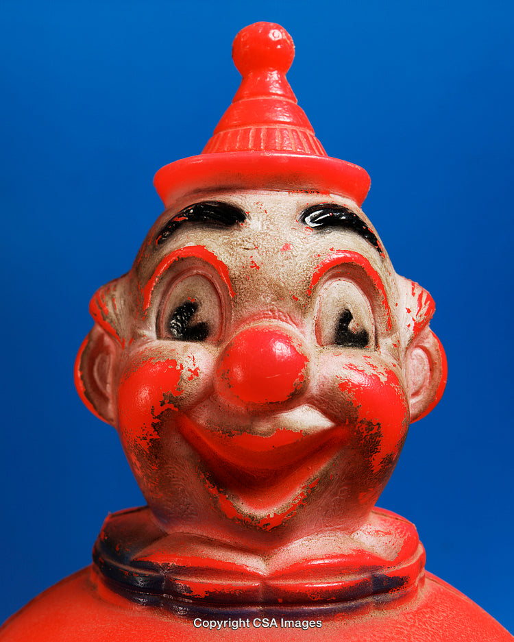 Vintage Red Clown Toy with Weathered Paint Against Blue Background