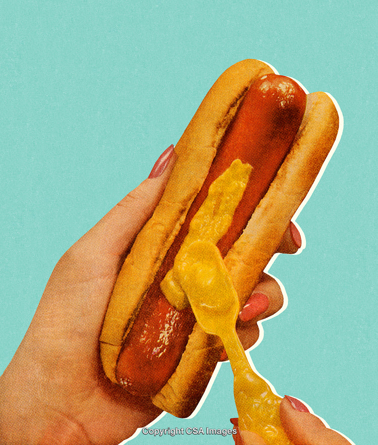 Close-Up of Person Adding Mustard to a Hot Dog on Blue Background