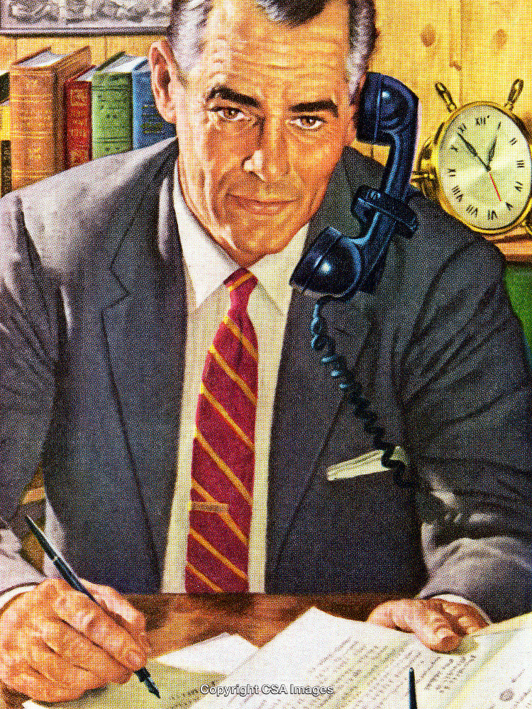 Professional Businessman Writing Notes While Speaking on a Landline Phone in an Office