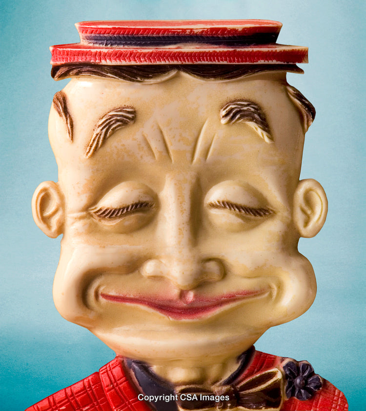 Vintage Ceramic Figure with Hat and Smiling Face Against a Blue Background