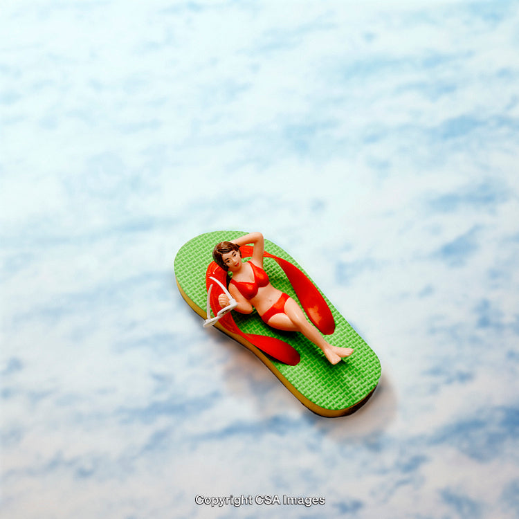 Miniature Woman Relaxing on Beach Styled as a Flip-Flop with Blue Background
