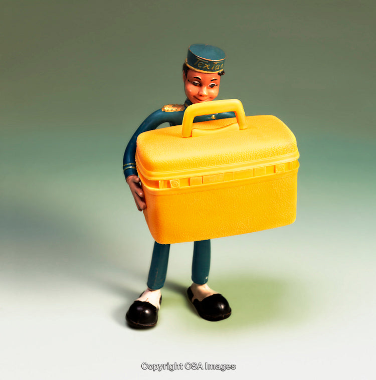 Vintage Bellhop Figurine Holding Bright Yellow Trunk on Neutral Background
