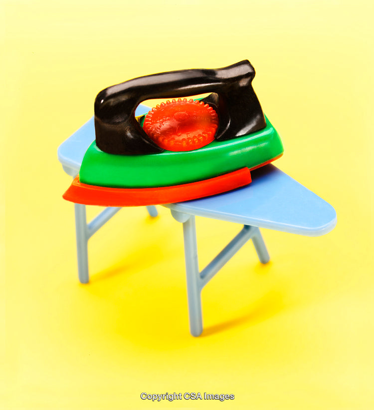 Colorful Plastic Toy Iron on Miniature Ironing Board with Yellow Background