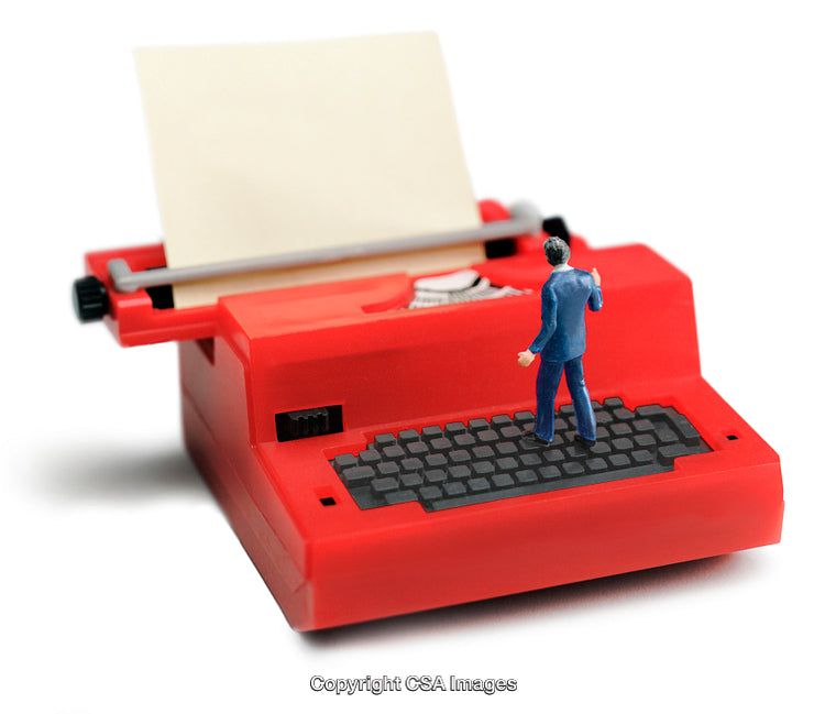 Small Figurine Standing on Large Red Toy Typewriter With Paper