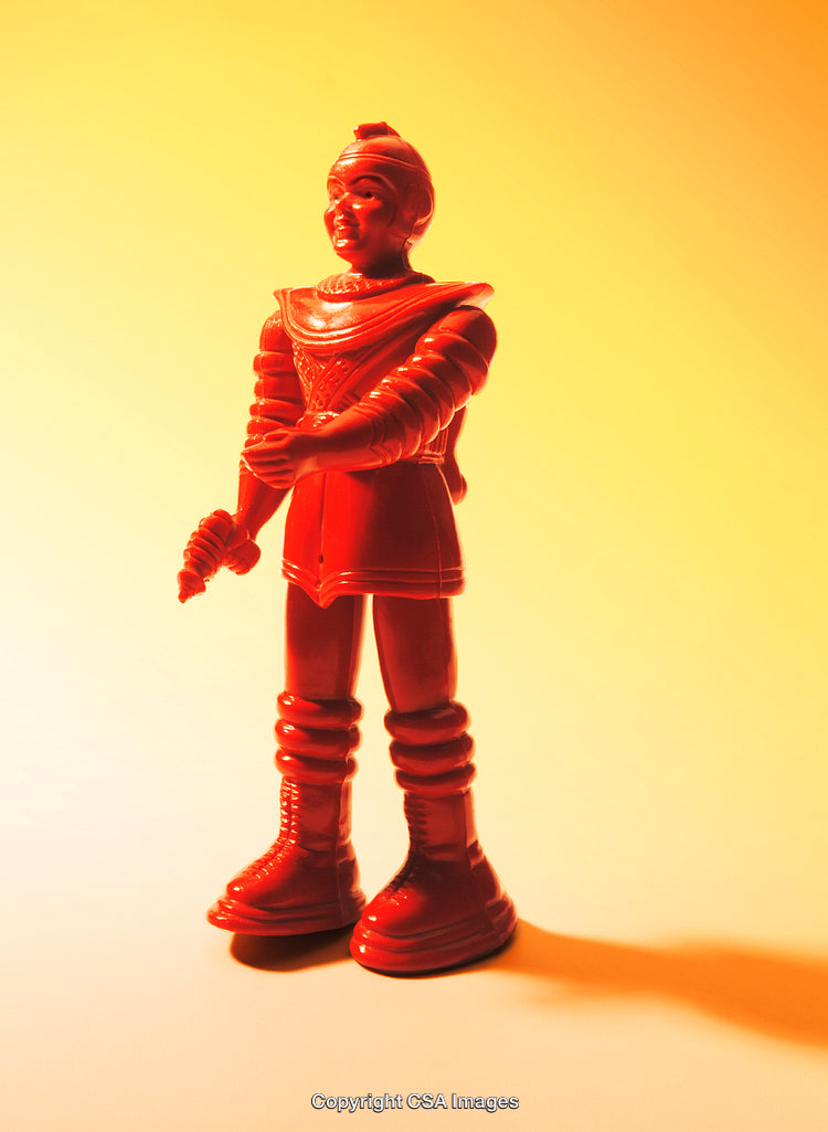 Red Plastic Toy Figure Against Vibrant Orange Background