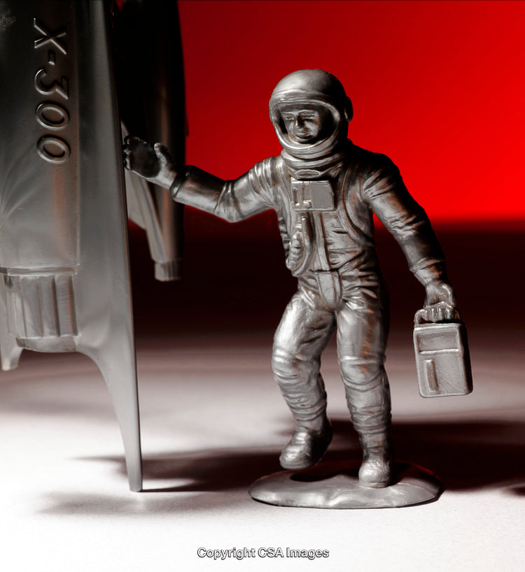 Plastic Astronaut Figure beside Spacecraft with Red Background