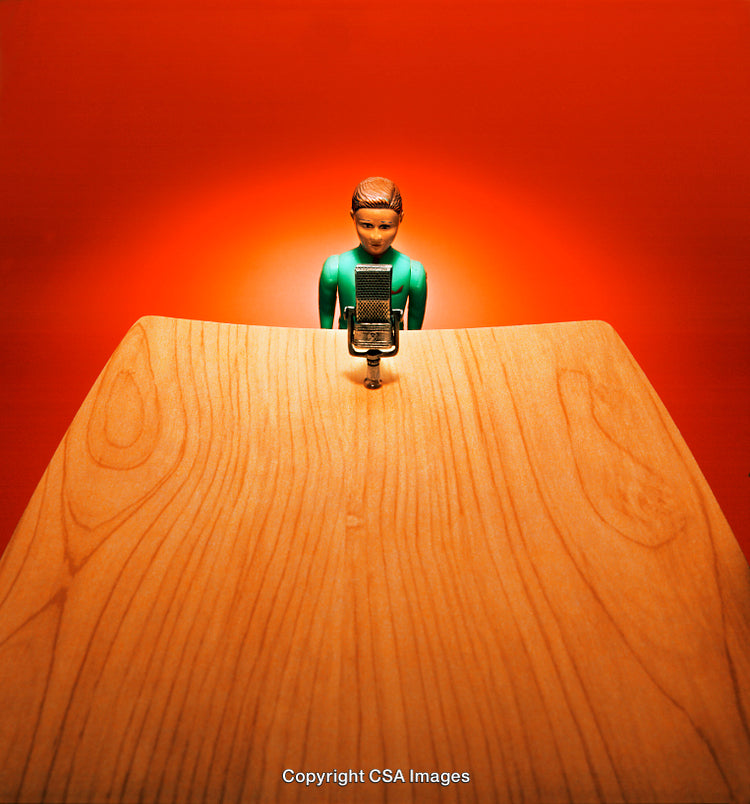 Toy Figure Speaking at a Microphone Against a Red Background