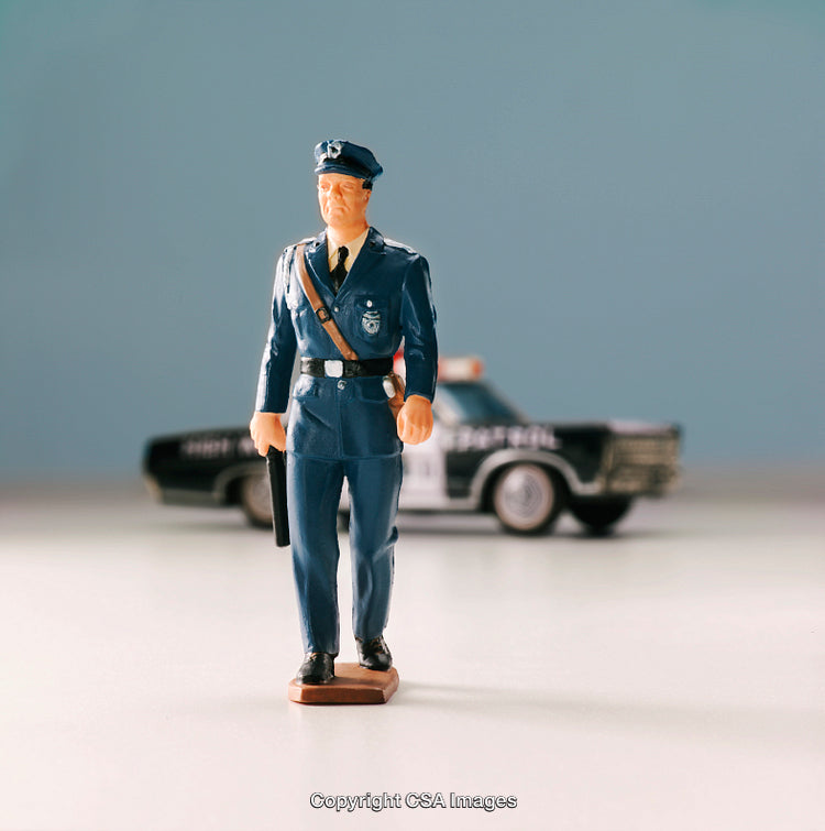 Plastic Police Officer Figurine with Toy Police Car in the Background