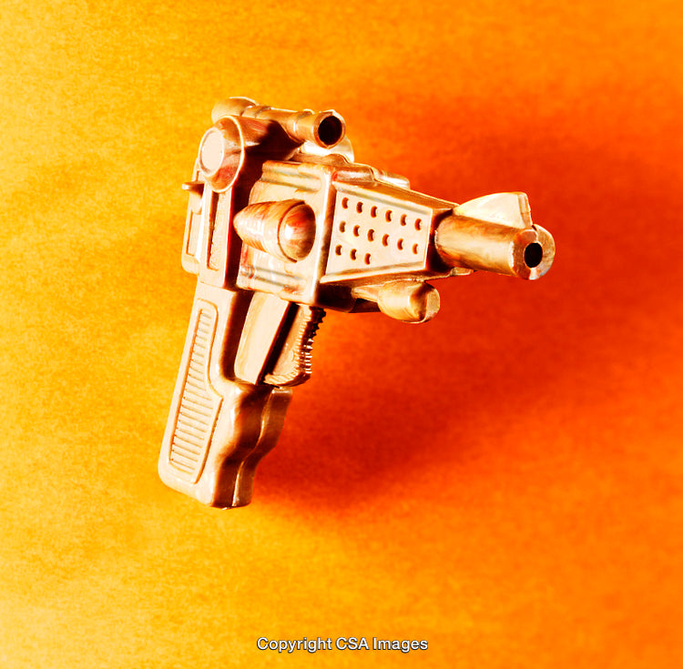 Golden Toy Ray Gun on Vibrant Orange Background for Creative Concepts