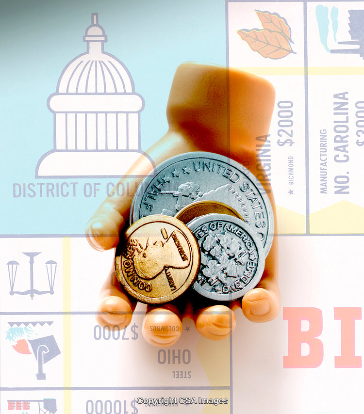 Hand Holding Coins Against Game Board with Monetary Symbols and Icons