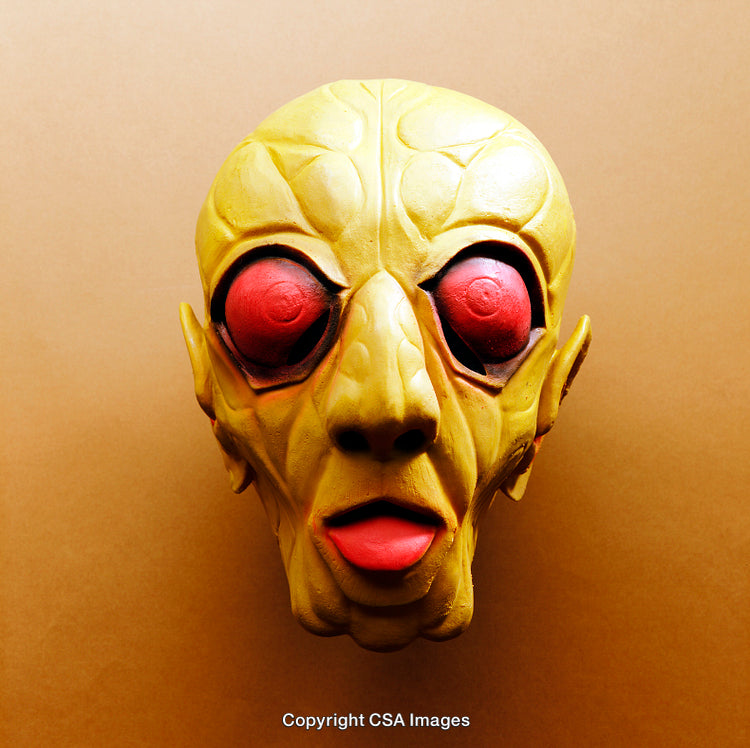 Close-Up of a Toy Alien Face with Red Eyes on Beige Background