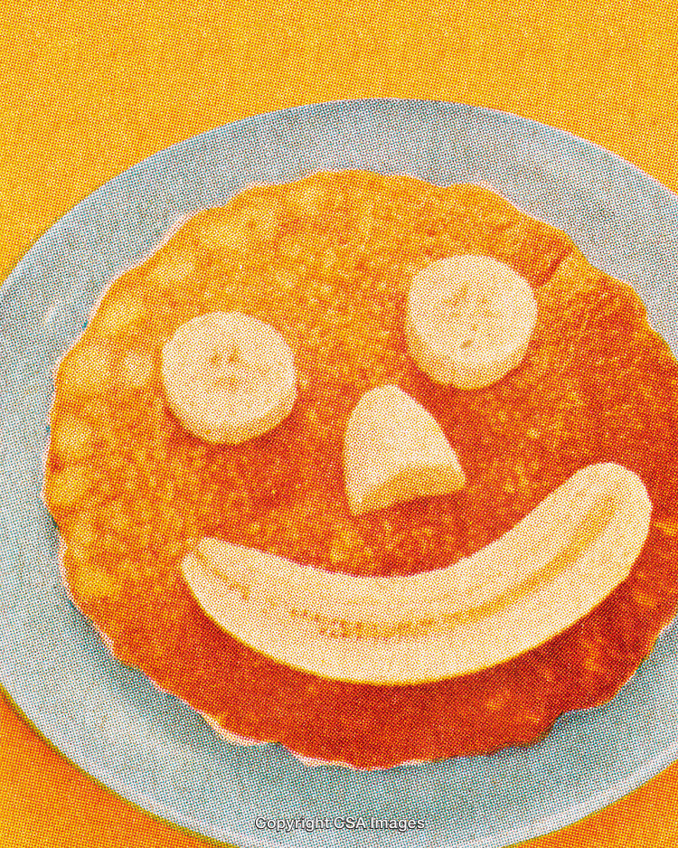 Smiling Pancake Breakfast with Banana Slices on a Vibrant Orange Background