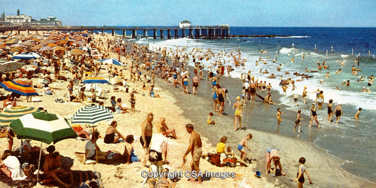 Crowded Sandy Beach with Colorful Umbrellas and Swimmers in the Ocean