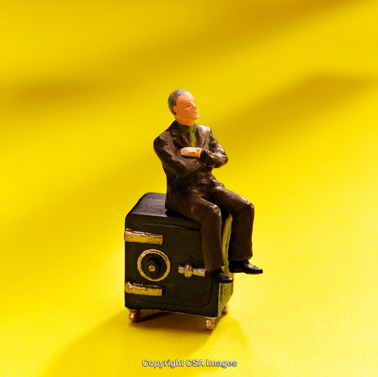 Small Figure Seated on Safe Against Bright Yellow Background