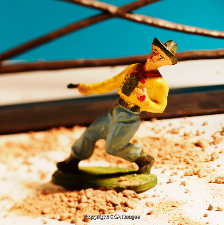Plastic Toy Cowboy Figure in Action on Sandy Terrain