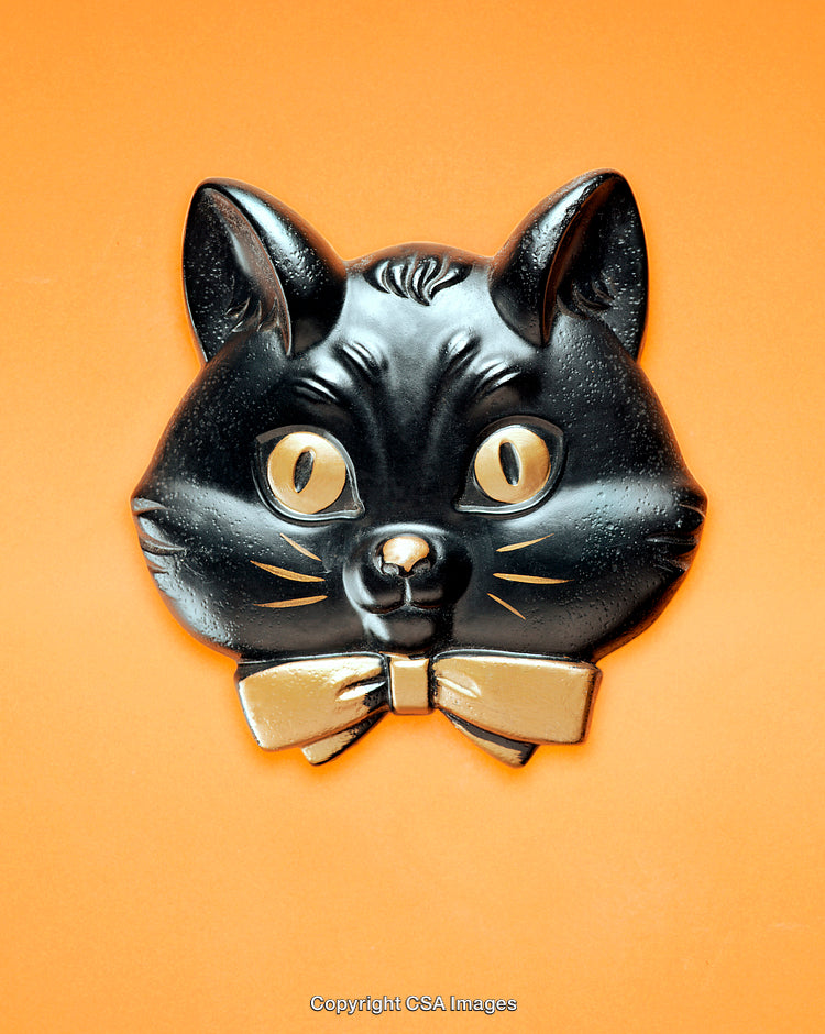 Black Cat Plastic Toy on Vibrant Orange Background with Golden Bow