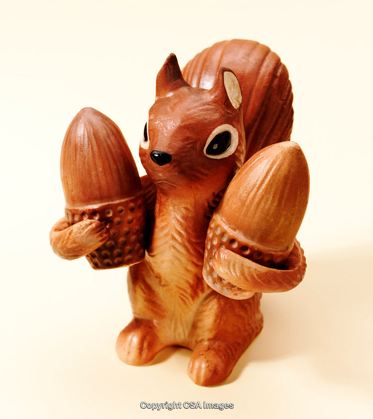 Brown Squirrel Figurine Holding Two Acorns on a Light Background